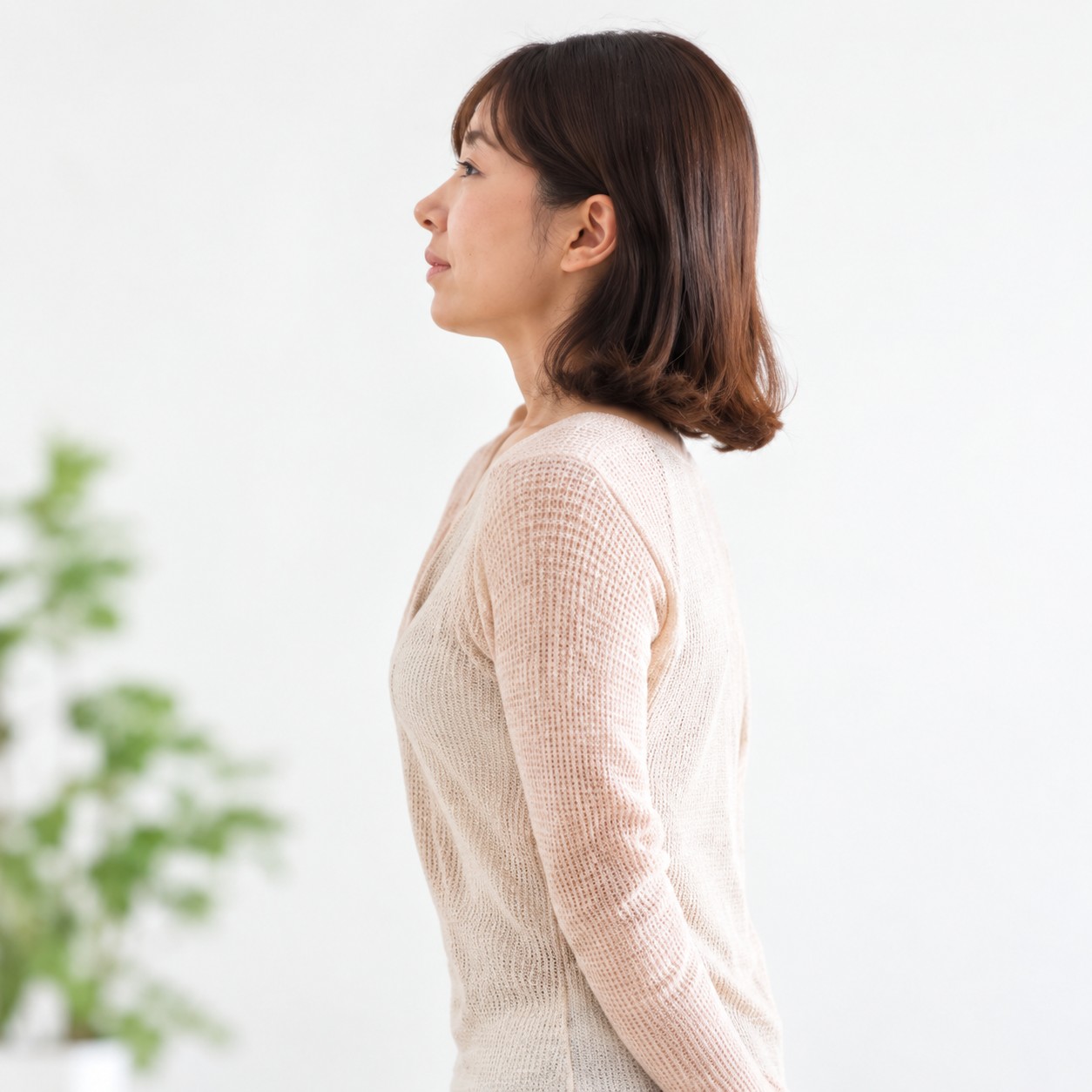 淡いベージュのニットを着た女性の左向きの横顔