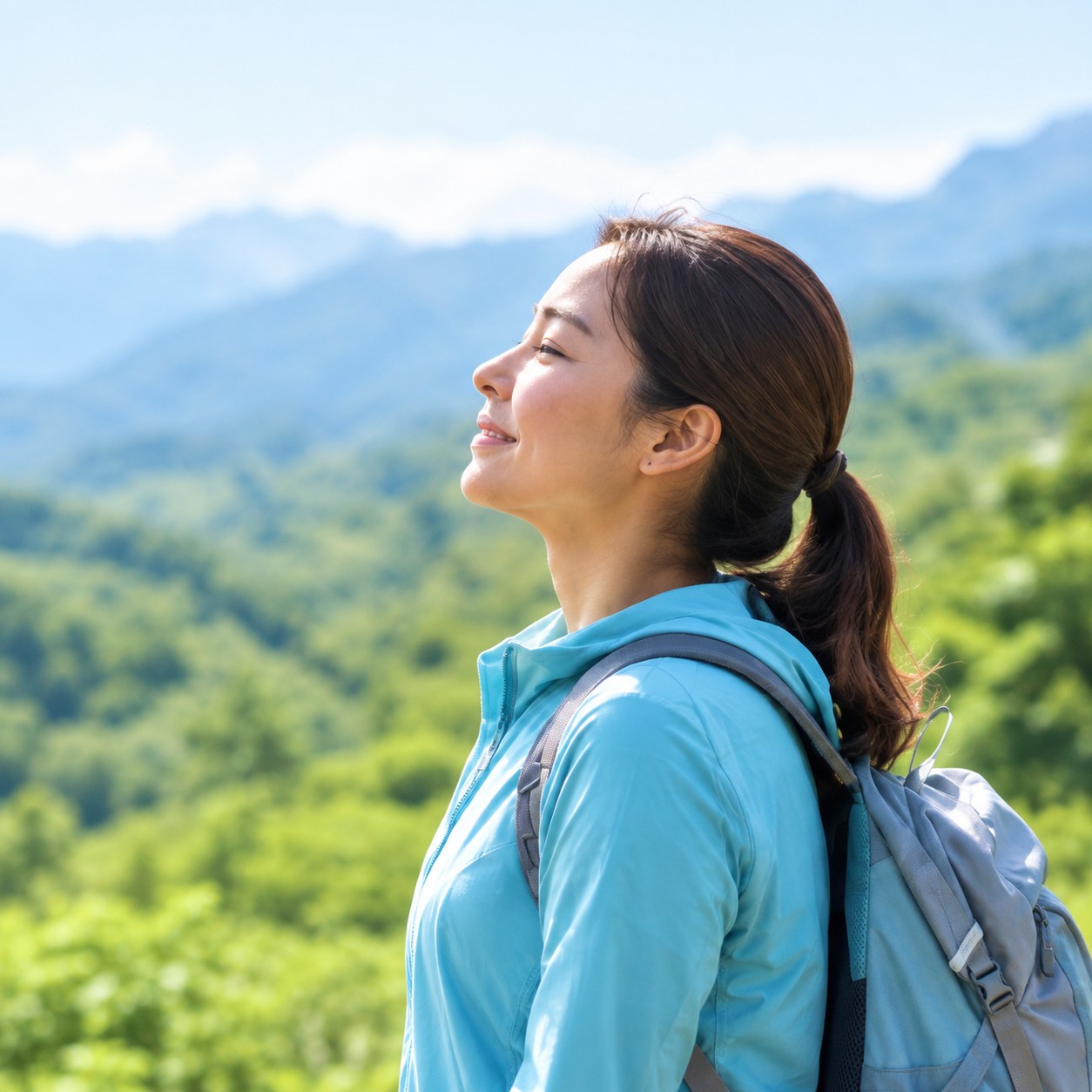 青い服とリュックの女性が山々を眺めている