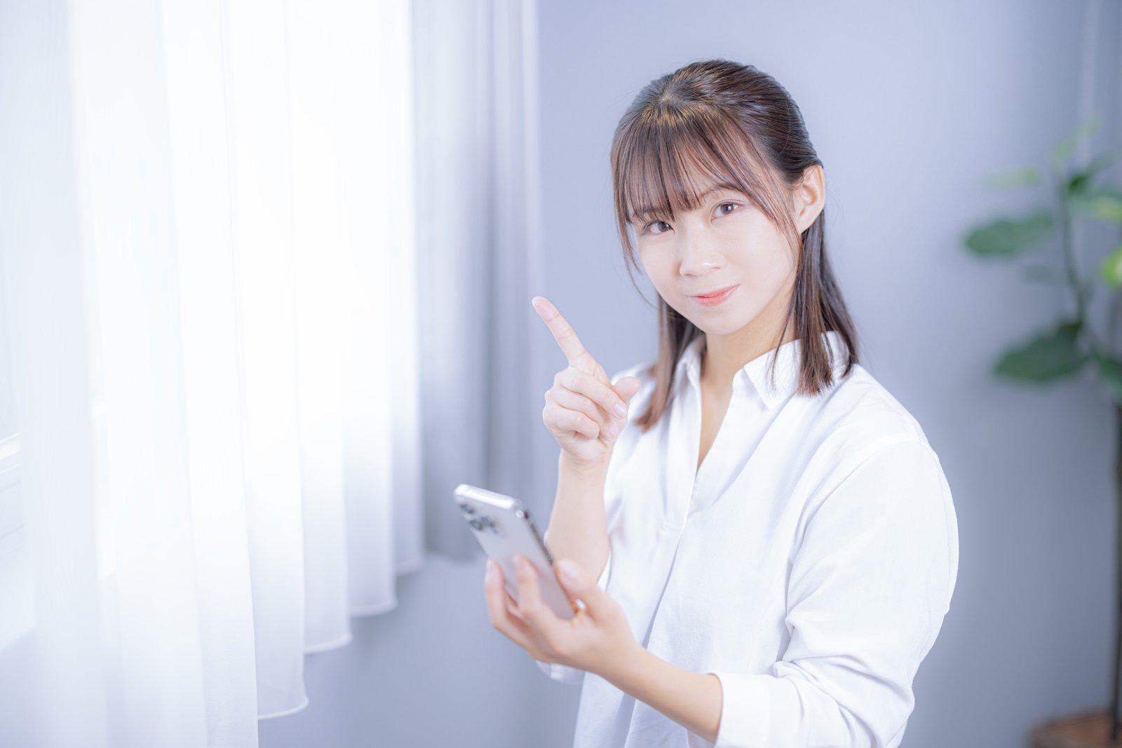 白いシャツの女性がスマートフォンを持ち指差している